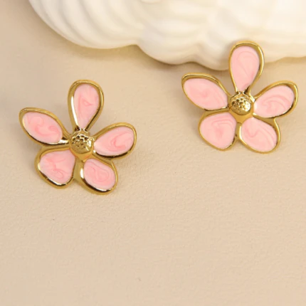 Boucles d'oreilles femme fleur dorées à cinq pétales rose poudré effet marbré sur fond beige