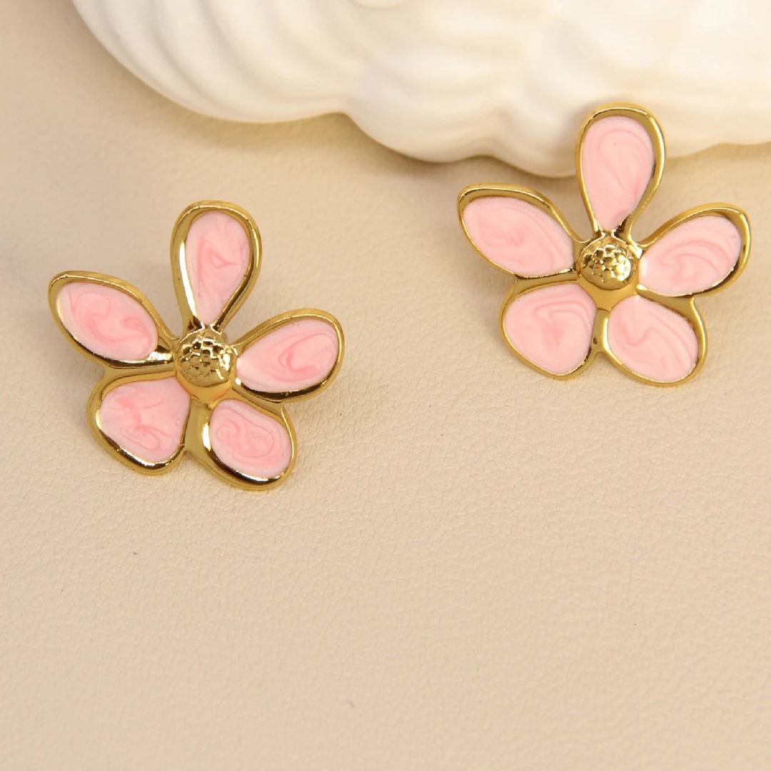 Boucles d'oreilles femme fleur dorées à cinq pétales rose poudré effet marbré sur fond beige