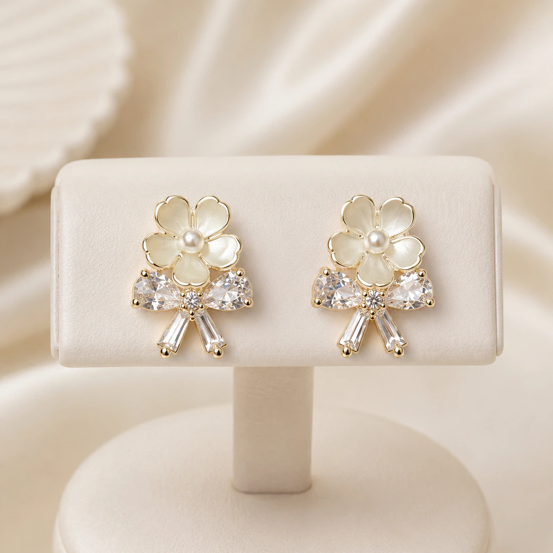 LV-BO-50 (2) Boucles d'oreilles puces dorées fleur ivoire à perle centrale et nœud de pierres transparentes sur présentoir