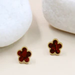 Paire de clous d'oreilles fleur rouge aux reflets marbrés et bordure dorée perlée entre des galets blancs