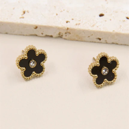 Boucles d'oreilles clous fleur noire dorées au contour perlé et strass central sur fond beige
