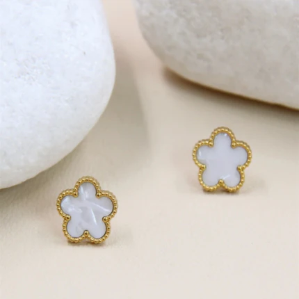 Boucles d'oreilles clous fleur blanche effet nacré dorées au contour perlé entre des galets blancs