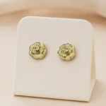 Boucles d'oreilles clous fleur crème dorées femme, pétales bordés de doré, sur présentoir