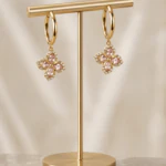 Boucles d'oreilles créoles dorées à pendentif trèfle en cristaux roses et strass sur présentoir