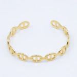 Bracelet jonc doré ouvert à maillons ovales type maille marine posé sur fond blanc