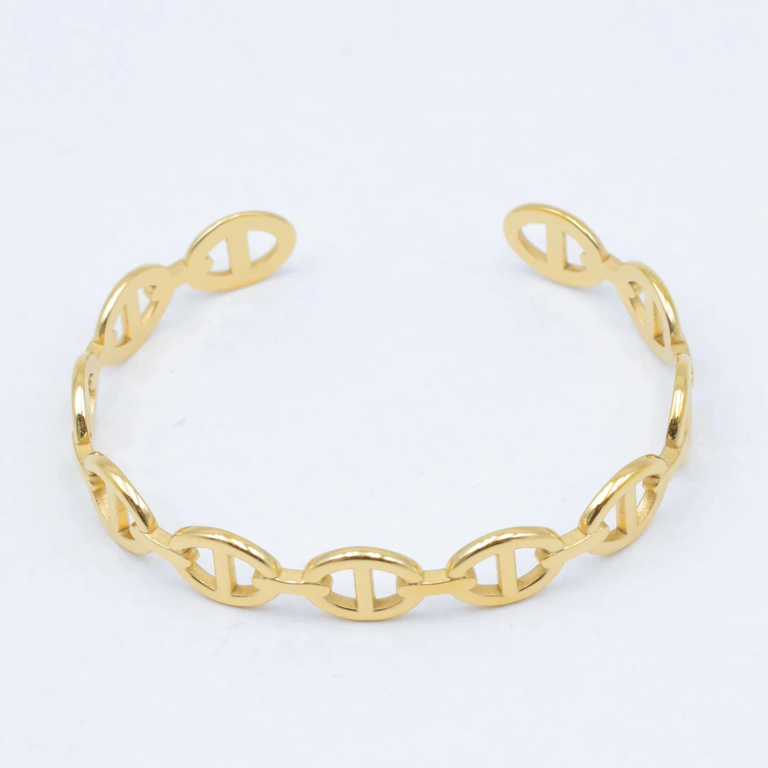Bracelet jonc doré ouvert à maillons ovales type maille marine posé sur fond blanc