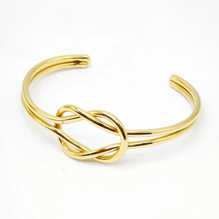 Bracelet jonc doré ouvert à double fil et nœud entrelacé central sur fond blanc