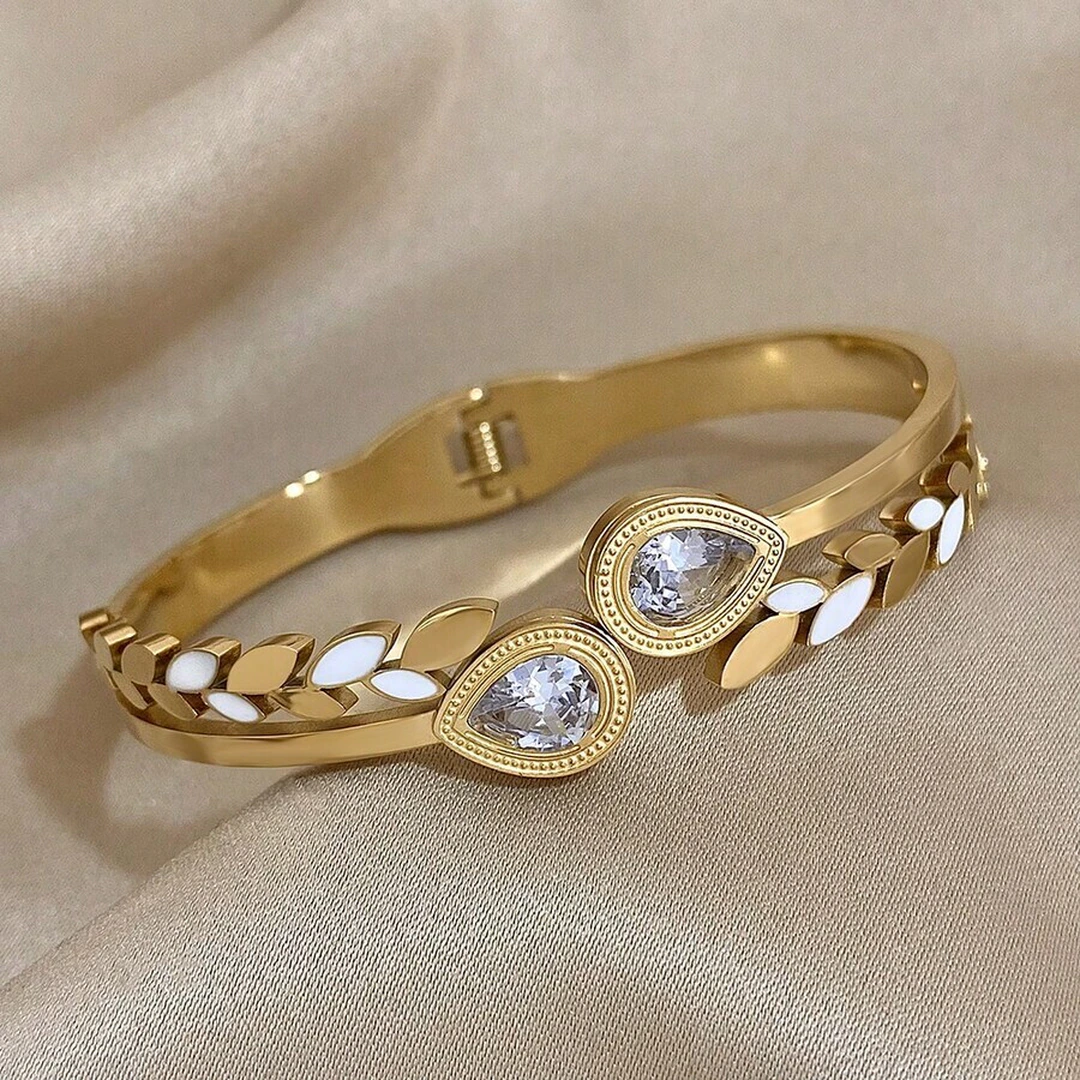 Vue de côté du bracelet jonc doré, feuillage blanc et doré autour de deux gouttes de cristal