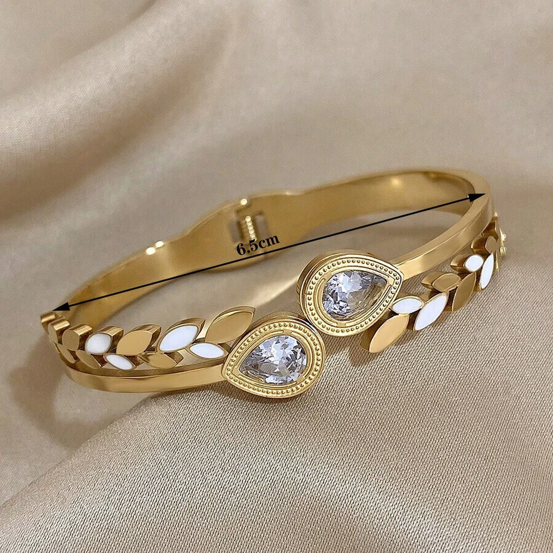 Bracelet jonc doré à feuilles blanches et cristaux en goutte avec son diamètre indiqué de 6,5 cm