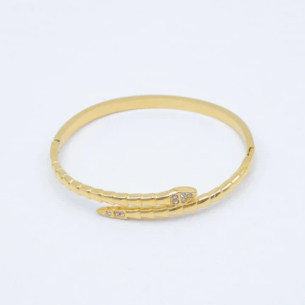 Bracelet jonc doré serpent enroulé à écailles, tête et queue serties de strass sur fond blanc