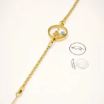 Bracelet chaîne torsadée dorée à médaillon transparent orné d'un serpent et d'un œil protecteur bleu