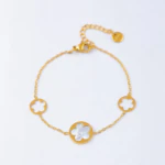 Bracelet chaîne fine dorée à médaillon fleur blanche effet nacré et deux fleurs ajourées, avec rallonge