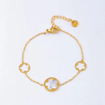 Bracelet chaîne fine dorée à médaillon fleur blanche effet nacré et deux fleurs ajourées, avec rallonge
