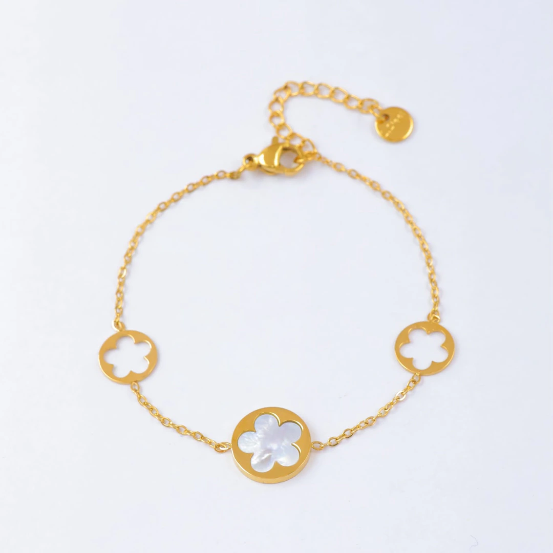 Bracelet chaîne fine dorée à médaillon fleur blanche effet nacré et deux fleurs ajourées, avec rallonge