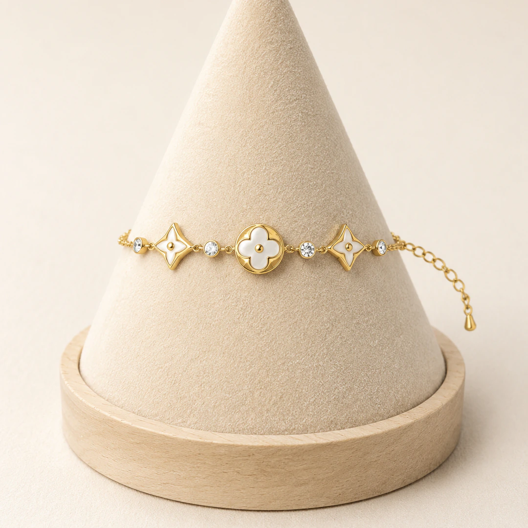 Bracelet chaîne dorée à médaillon trèfle blanc, étoiles blanches et strass sur un présentoir cône