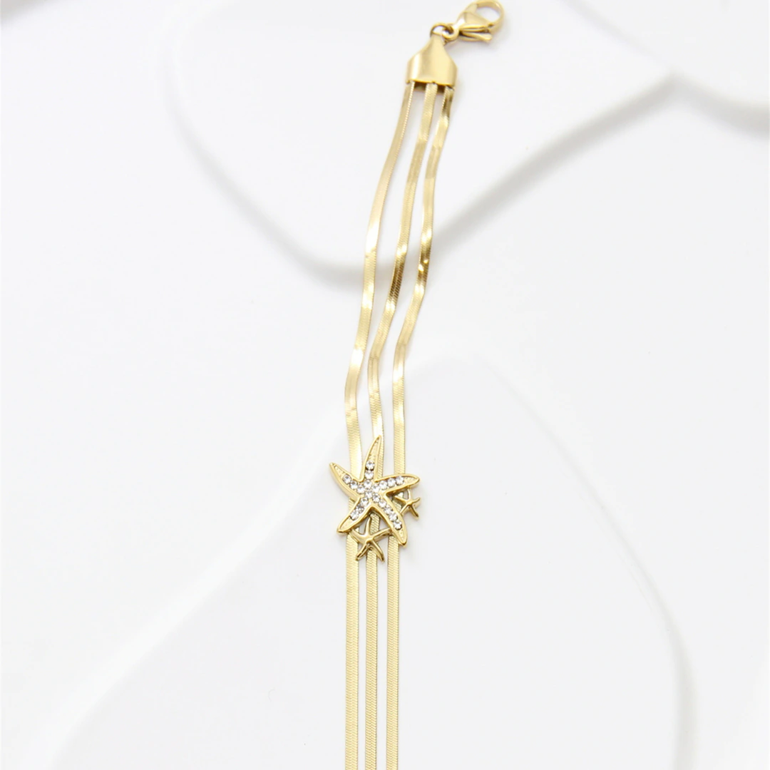 Bracelet trois rangs de chaînes plates dorées avec étoile de mer strassée et fermoir mousqueton