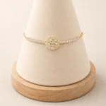 Bracelet doré à ligne de strass et rosace de cristaux baguette sur un présentoir cône beige