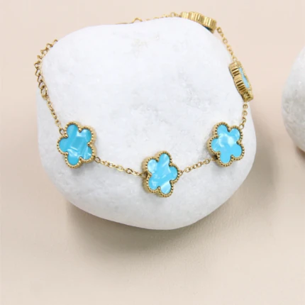 Motifs fleur bleu turquoise effet marbré du bracelet doré posé sur un galet blanc
