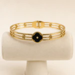 Bracelet jonc trèfle noir sur présentoir, vue des barres dorées et des petits trèfles ajourés