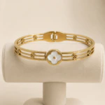 Bracelet jonc à trèfle blanc sur présentoir, vue du fermoir à charnière et des motifs ajourés