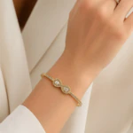 Bracelet jonc fin doré porté au poignet, détail du motif infini serti de pierres claires