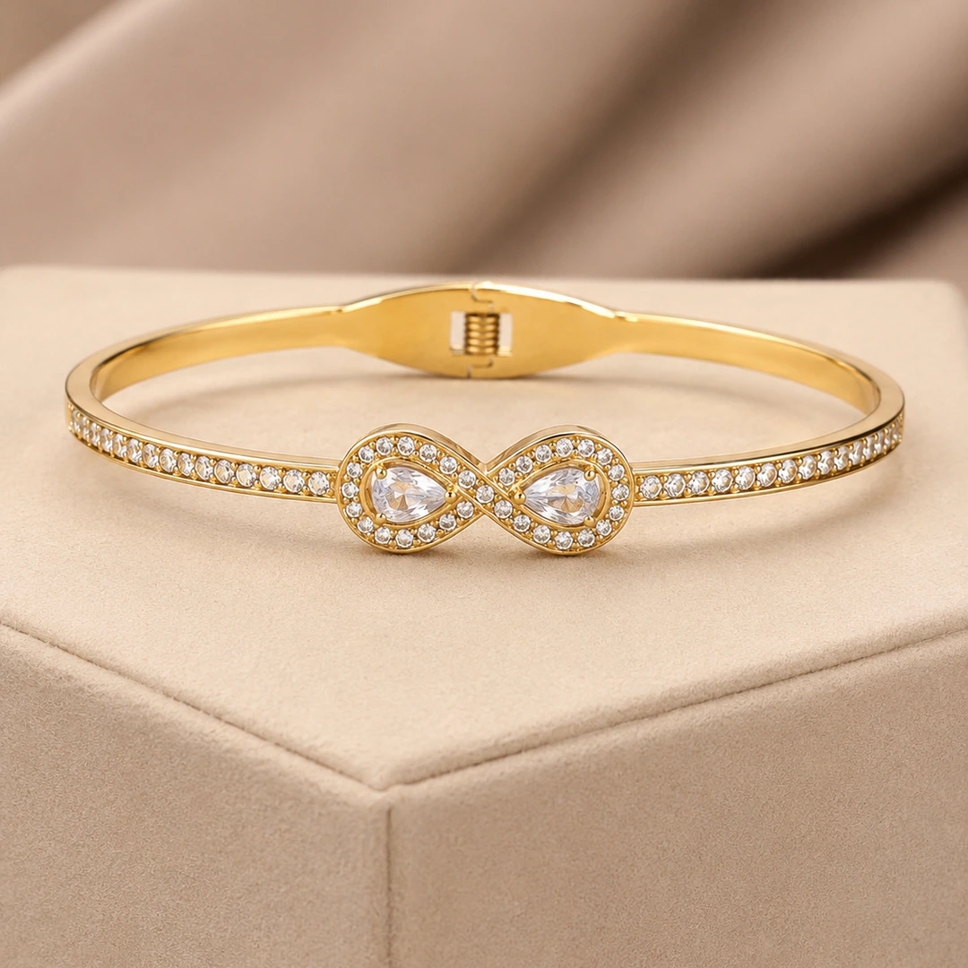 Bracelet jonc doré femme motif infini à deux gouttes en cristal et rangée de pierres claires, sur velours beige