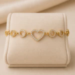 Bracelet cœur ajouré et cercles brillants dorés présenté à plat sur un présentoir en velours beige
