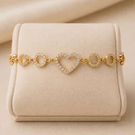 Bracelet cœur ajouré et cercles brillants dorés présenté à plat sur un présentoir en velours beige