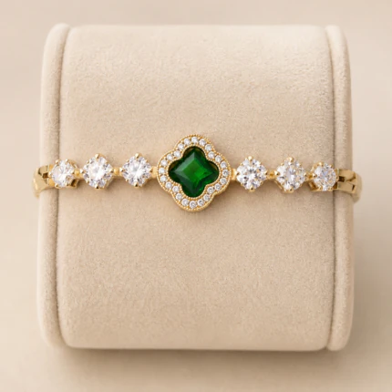 Bracelet trèfle vert à pierres claires rondes sur présentoir en velours beige, vue rapprochée