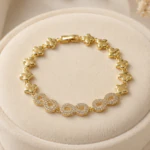 Bracelet à maillons trèfles dorés et trois infinis brillants posé sur un présentoir rond en velours