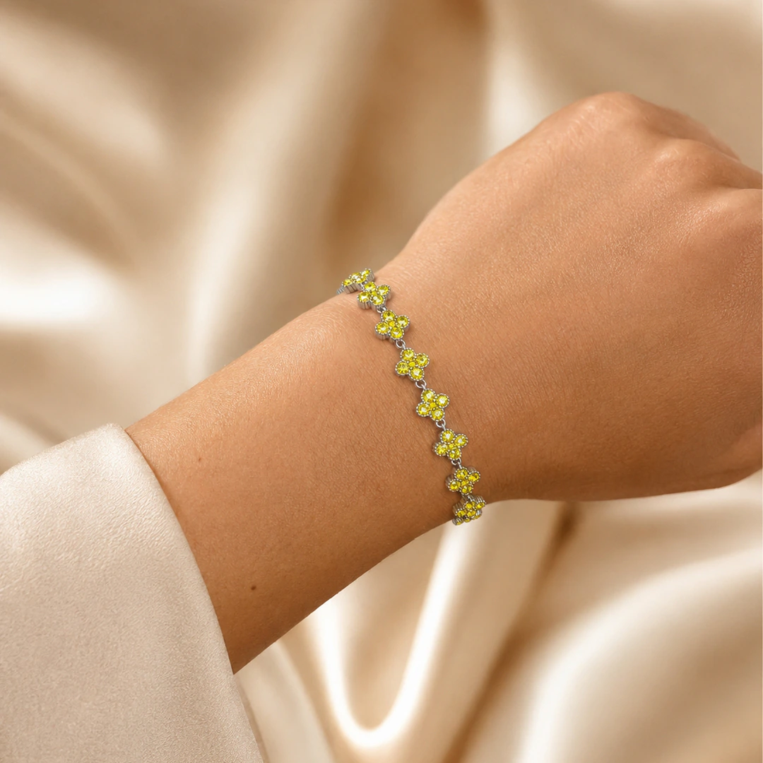 Bracelet argenté porté au poignet, vue des maillons en forme de trèfle sertis de strass jaunes