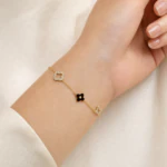 Bracelet chaîne fine doré femme à trèfle noir, trèfle et étoile ajourés en strass, porté au poignet