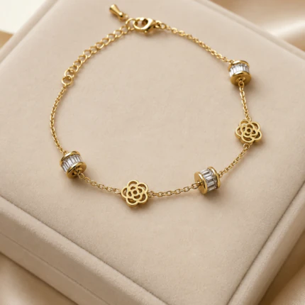 Bracelet chaîne fine doré femme à fleurs ajourées et perles serties de strass baguette, sur un écrin