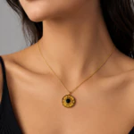 Collier chaîne fine doré à médaillon rond et pierre noire porté au cou sur un haut noir