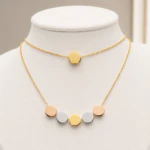 Collier deux rangs à disque doré et rangée de pastilles rose doré, argentées et dorées sur buste