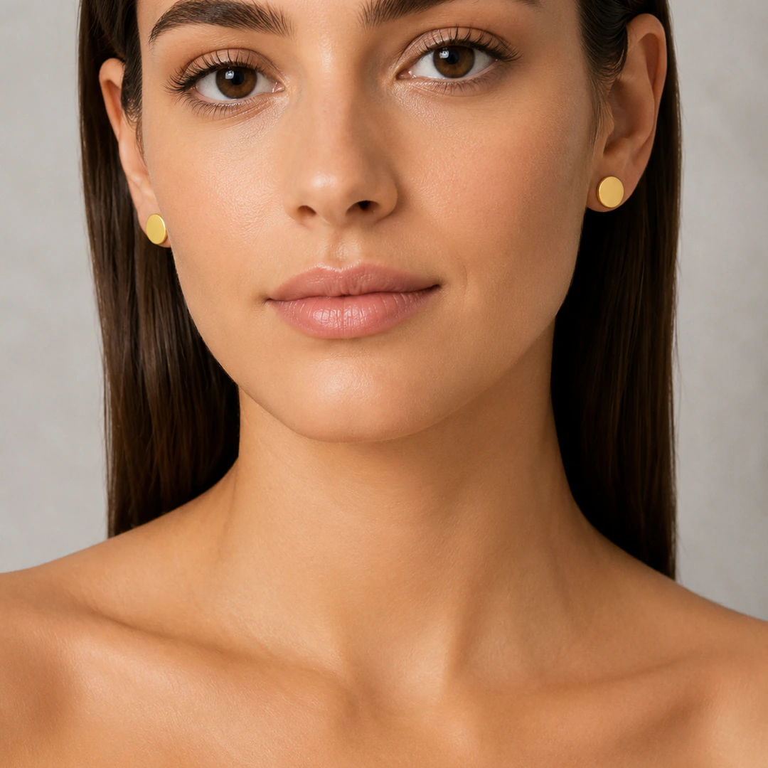 Femme portant des puces d'oreilles rondes dorées minimalistes, vue de face