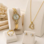 Parure du coffret bijoux doré femme : montre à strass, collier cœur ajouré, bague et puces sur présentoirs