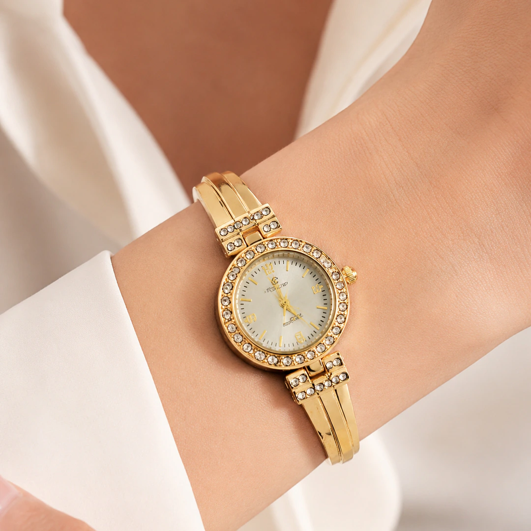 Montre femme dorée à cadran clair et lunette sertie de strass portée au poignet