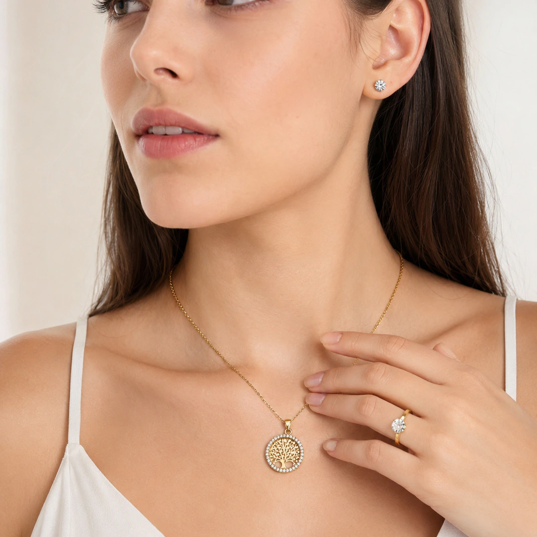 Femme portant un collier arbre de vie doré, une bague solitaire et des puces d'oreilles cristal