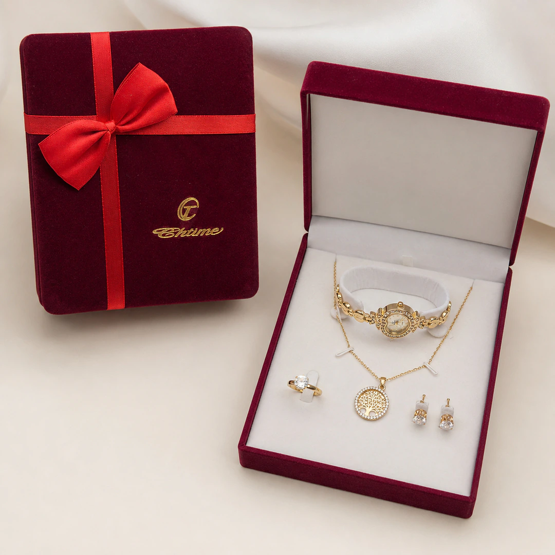 Écrin bordeaux ouvert avec montre cœur dorée, collier arbre de vie, bague et puces d'oreilles