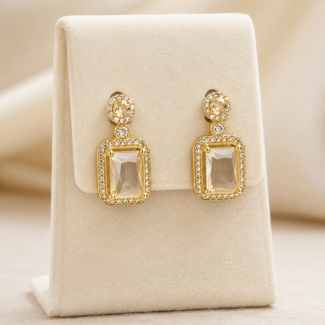Boucles d'oreilles pendantes dorées à pierre rectangulaire facettée et strass sur présentoir