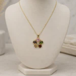 Collier chaîne fine doré à pendentif fleur multicolore sur buste de présentation beige