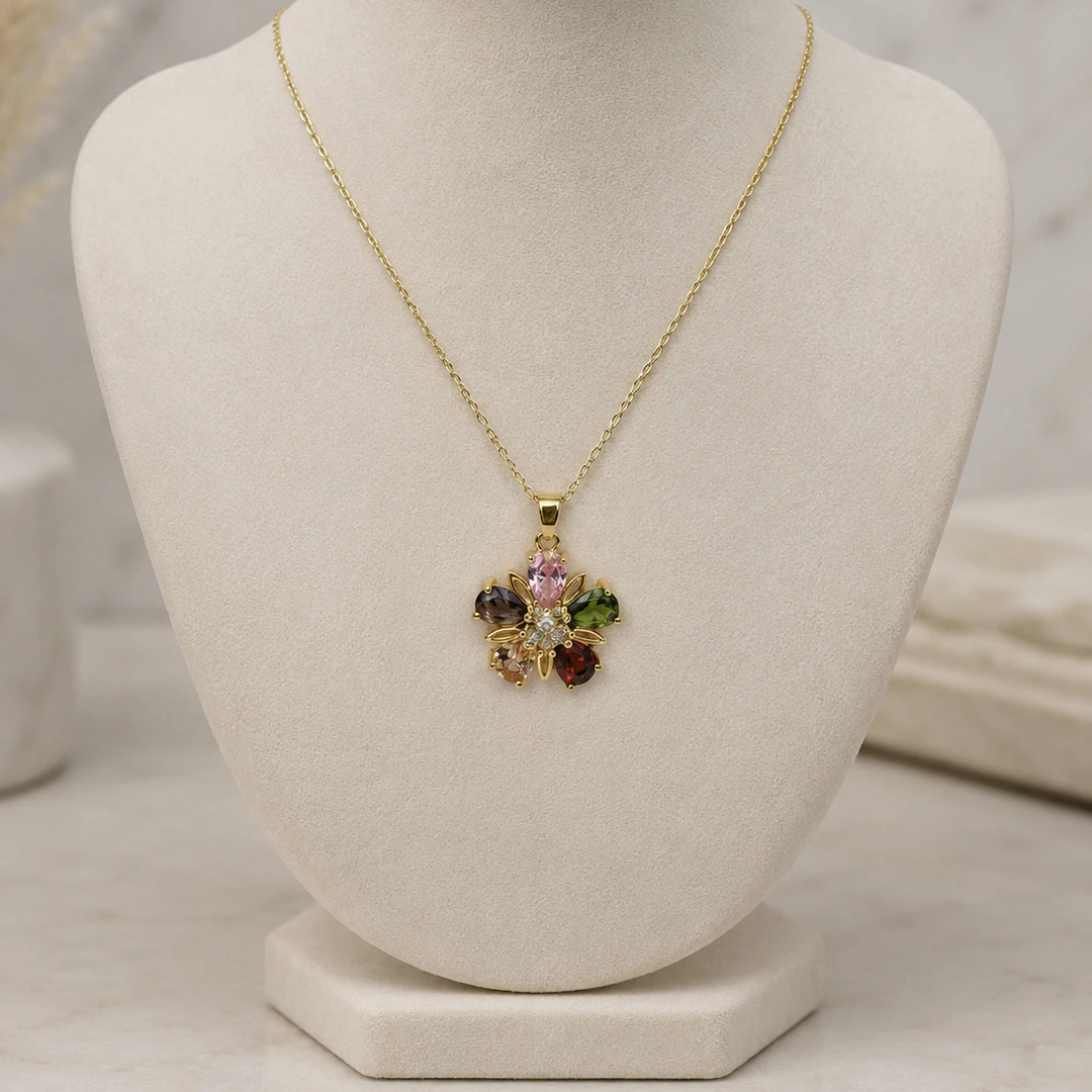 Collier chaîne fine doré à pendentif fleur multicolore sur buste de présentation beige