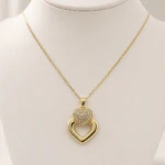 Collier femme doré à pendentif cœur ajouré surmonté d'un cœur pavé de strass sur buste