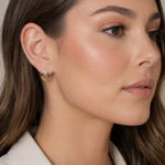 Boucle d'oreille double cœur dorée portée à l'oreille, femme vue de profil