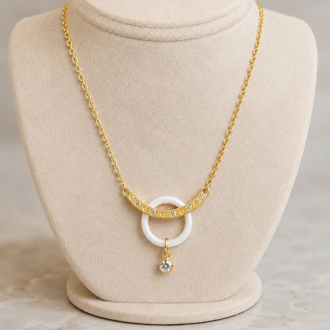 Collier pendentif anneau blanc et barre dorée incurvée sertie de strass sur buste beige