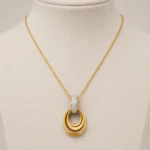 Collier chaîne fine doré à pendentif ovale ajouré sur buste beige, vue de face