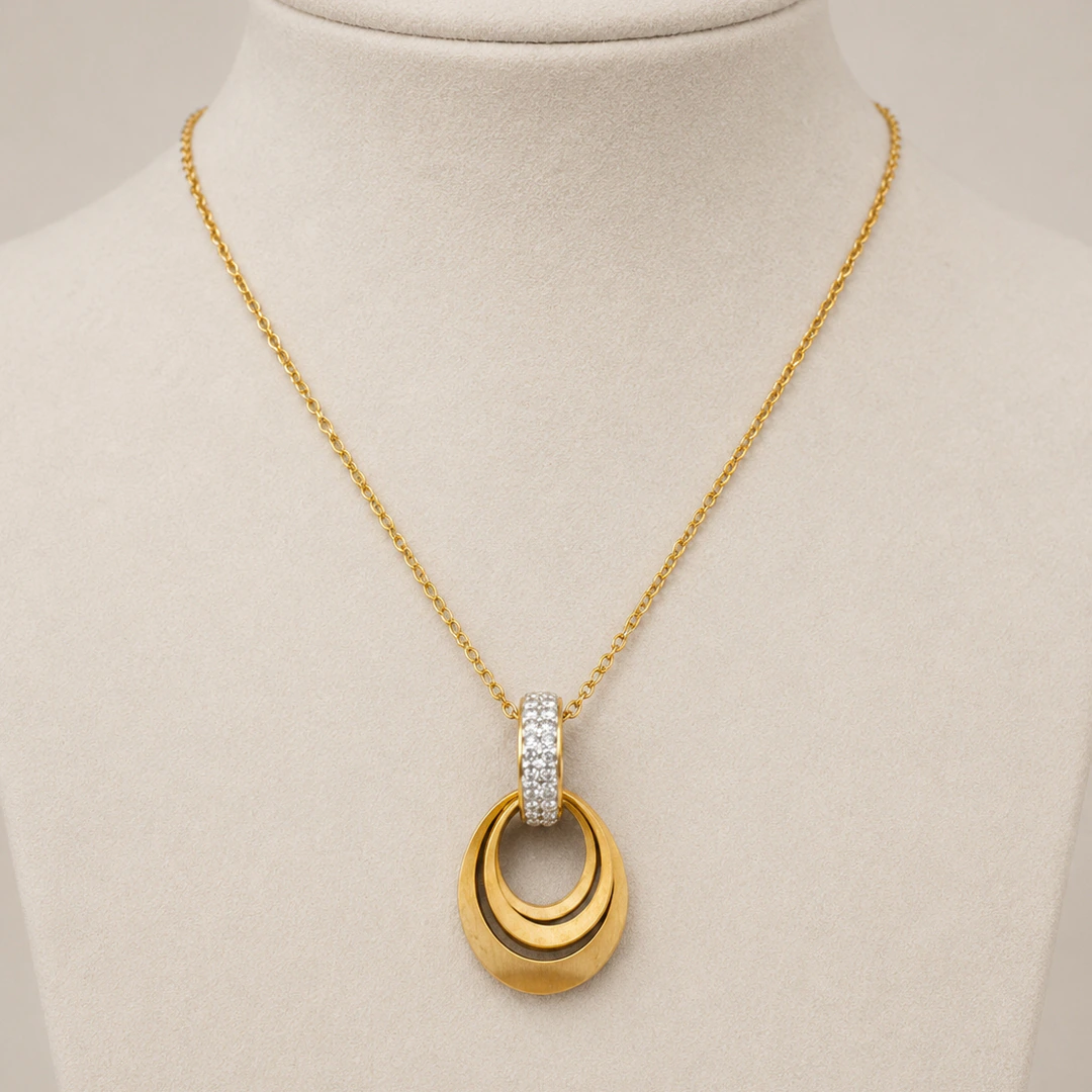 Collier chaîne fine doré à pendentif ovale ajouré sur buste beige, vue de face