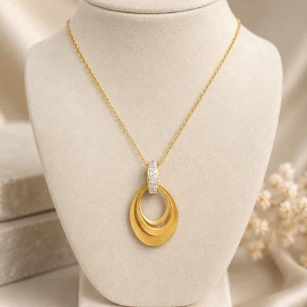 Pendentif doré à ovales superposés effet satiné et bélière à strass sur buste de présentation
