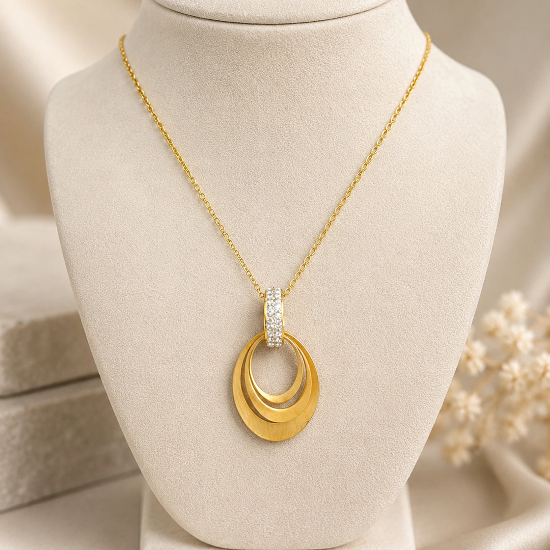 Pendentif doré à ovales superposés effet satiné et bélière à strass sur buste de présentation